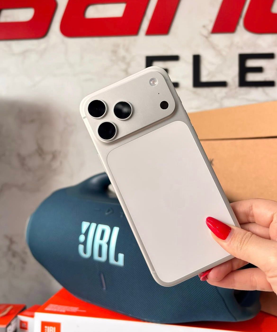 iPhone branco com JBL ao fundo